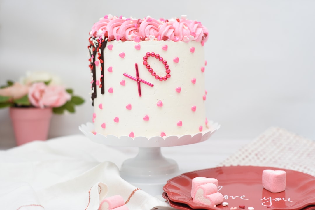 A round pink and white iced cake with delicate piped detail, the kind of polished finish families often choose for a quinceanera cake