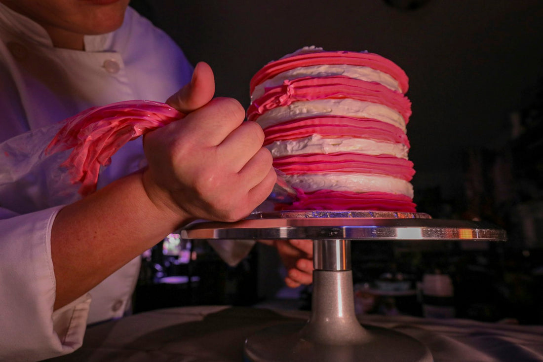 Baker piping custom buttercream decoration onto a designer cake