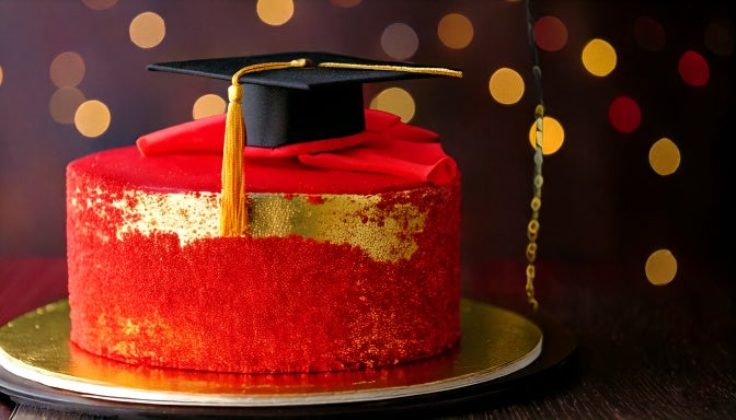 Graduation cake in cardinal red and gold with a graduation cap topper