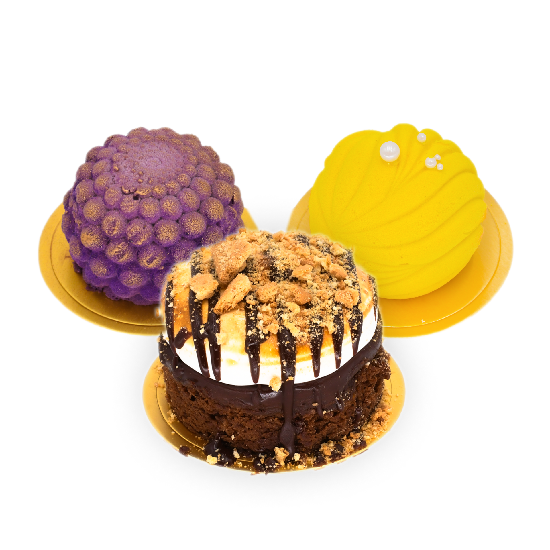 Three elegant cakes on gold plates: a purple dome-shaped cake, a yellow swirled cake with a pearl decoration, and a chocolate cake topped with cream, chocolate drizzle, and crumbled cookies.