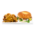 Gourmet sandwich bagel with prosciutto, arugula, cheese and avocado, served with chips drizzled with sauce on a white platter.