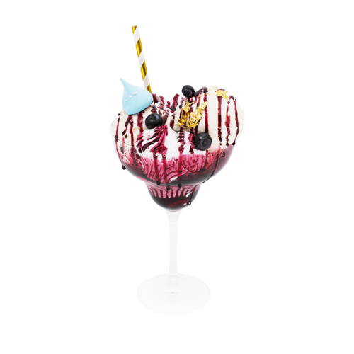 Handcrafted gourmet dessert in a glass with blueberries, whipped cream, gold leaf, and berry sauce.