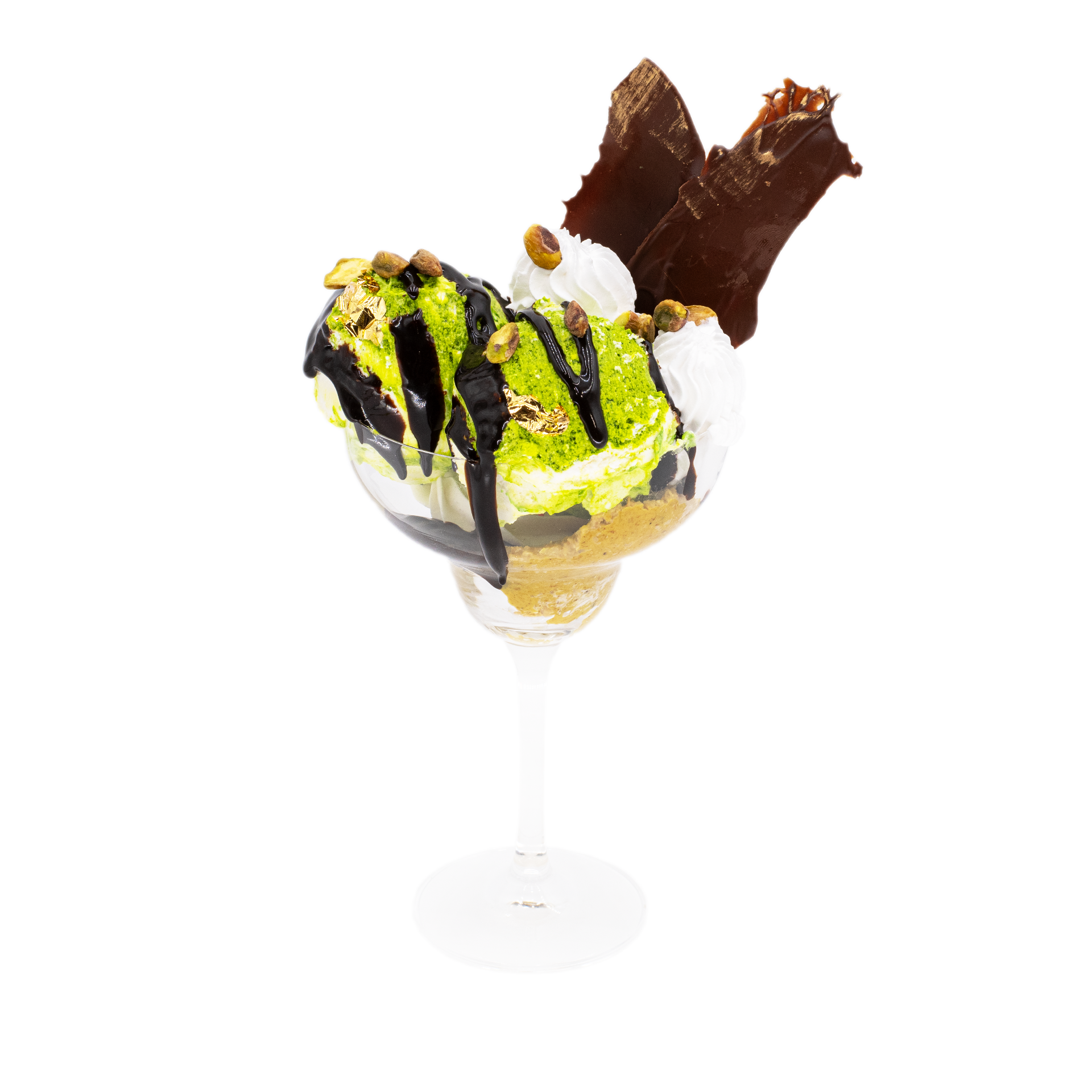 Pistachio ice cream sundae in a glass with chocolate sauce, nuts, whipped cream, and chocolate shards