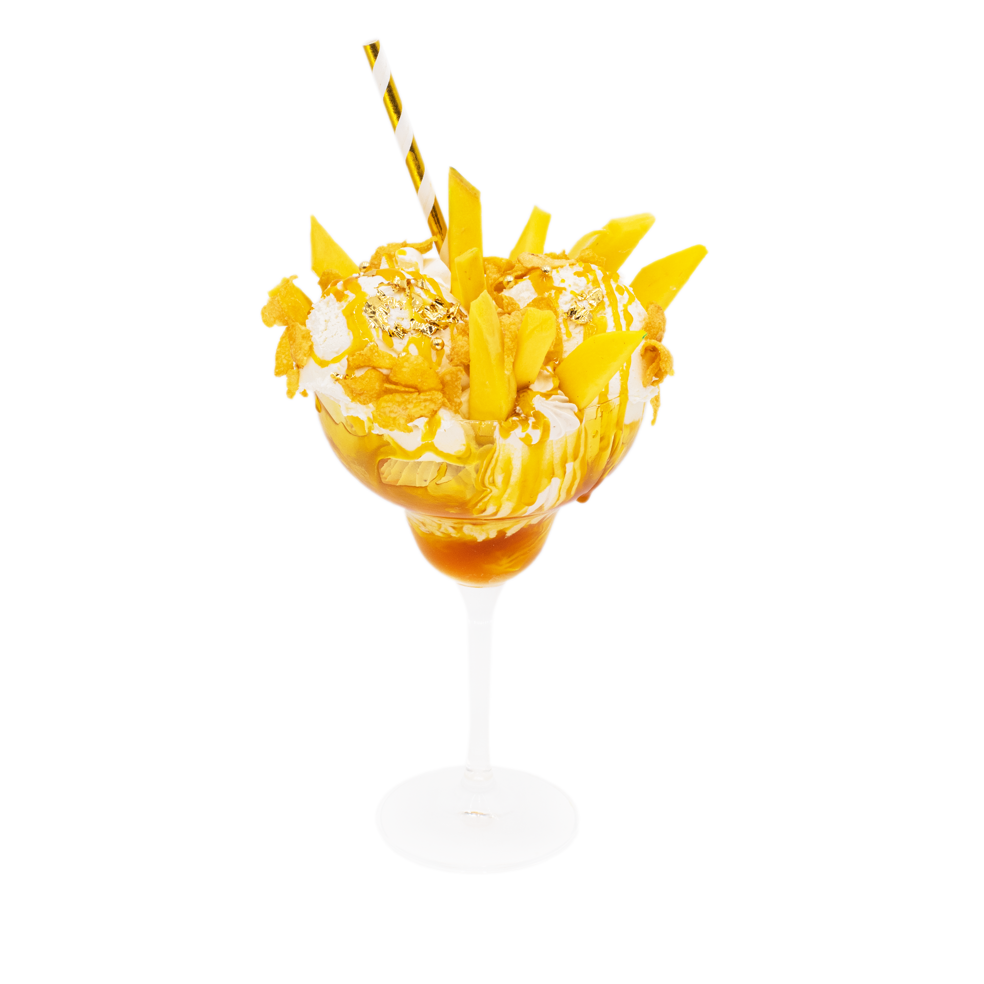 Mango sundae dessert with whipped cream, caramel drizzle, and gold flakes in a glass