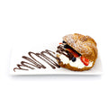 Croissant filled with whipped cream, strawberries, blueberries, and chocolate drizzle on a white plate