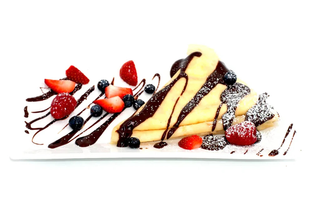 Crepes with chocolate sauce, fresh strawberries, blueberries, and powdered sugar on a plate