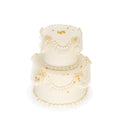 Two-tier white custom cake with gold accents and piped buttercream decorations