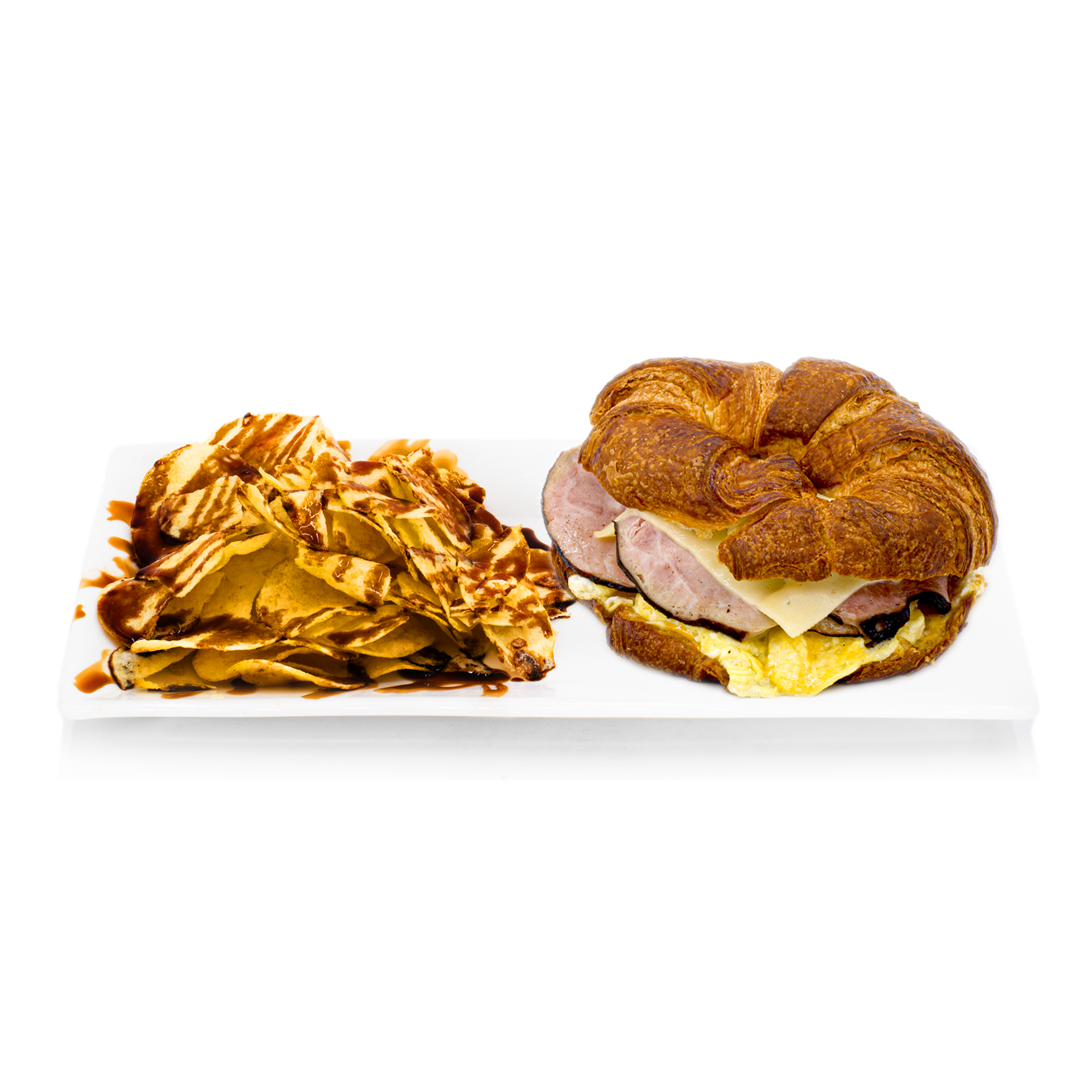 Croissant breakfast sandwich with ham, cheese, and eggs served with chips and sauce on a white plate