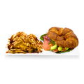 Smoked salmon and avocado croissant sandwich with potato chips on white plate