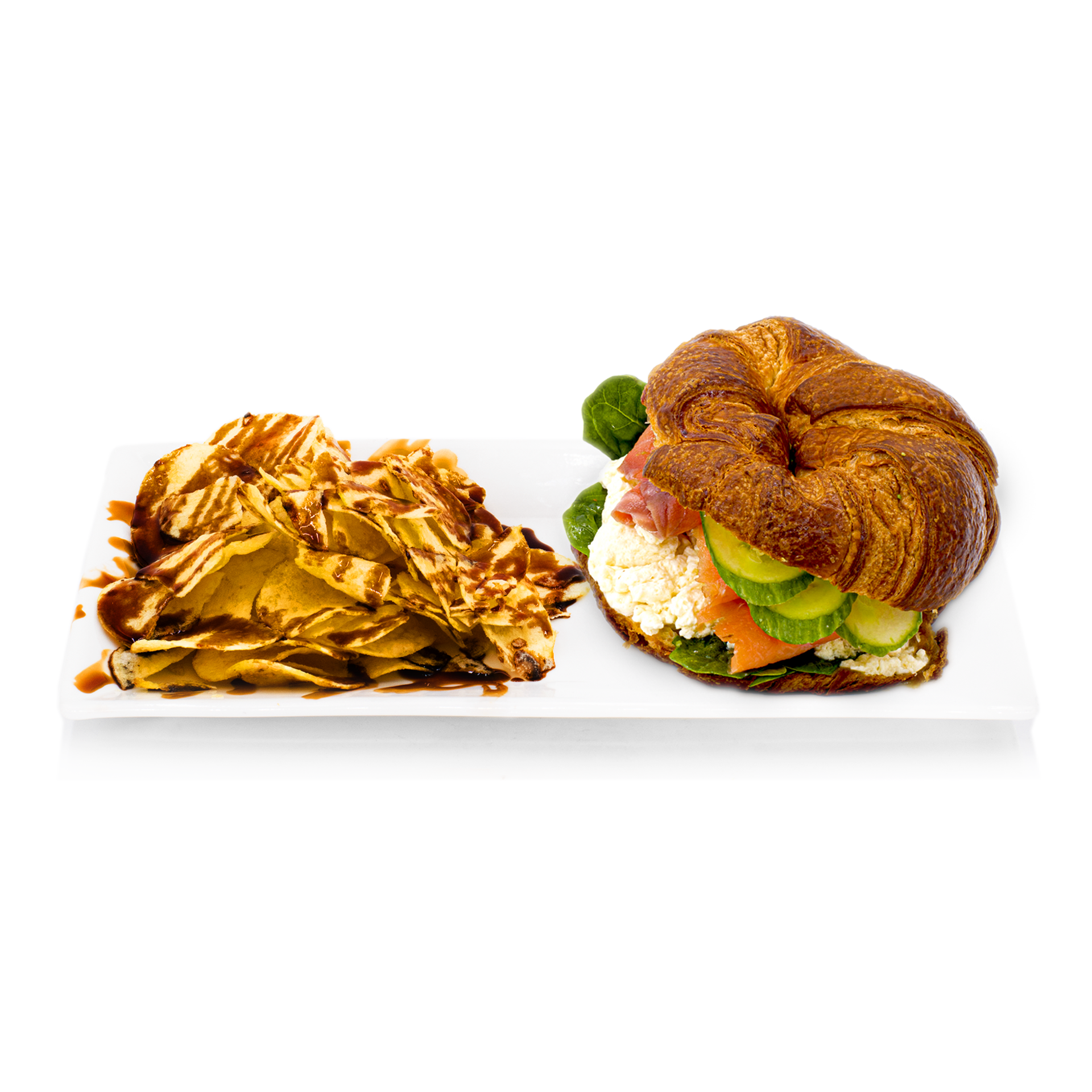Croissant sandwich with smoked salmon, cucumber, spinach and chips drizzled with sauce on a white plate.