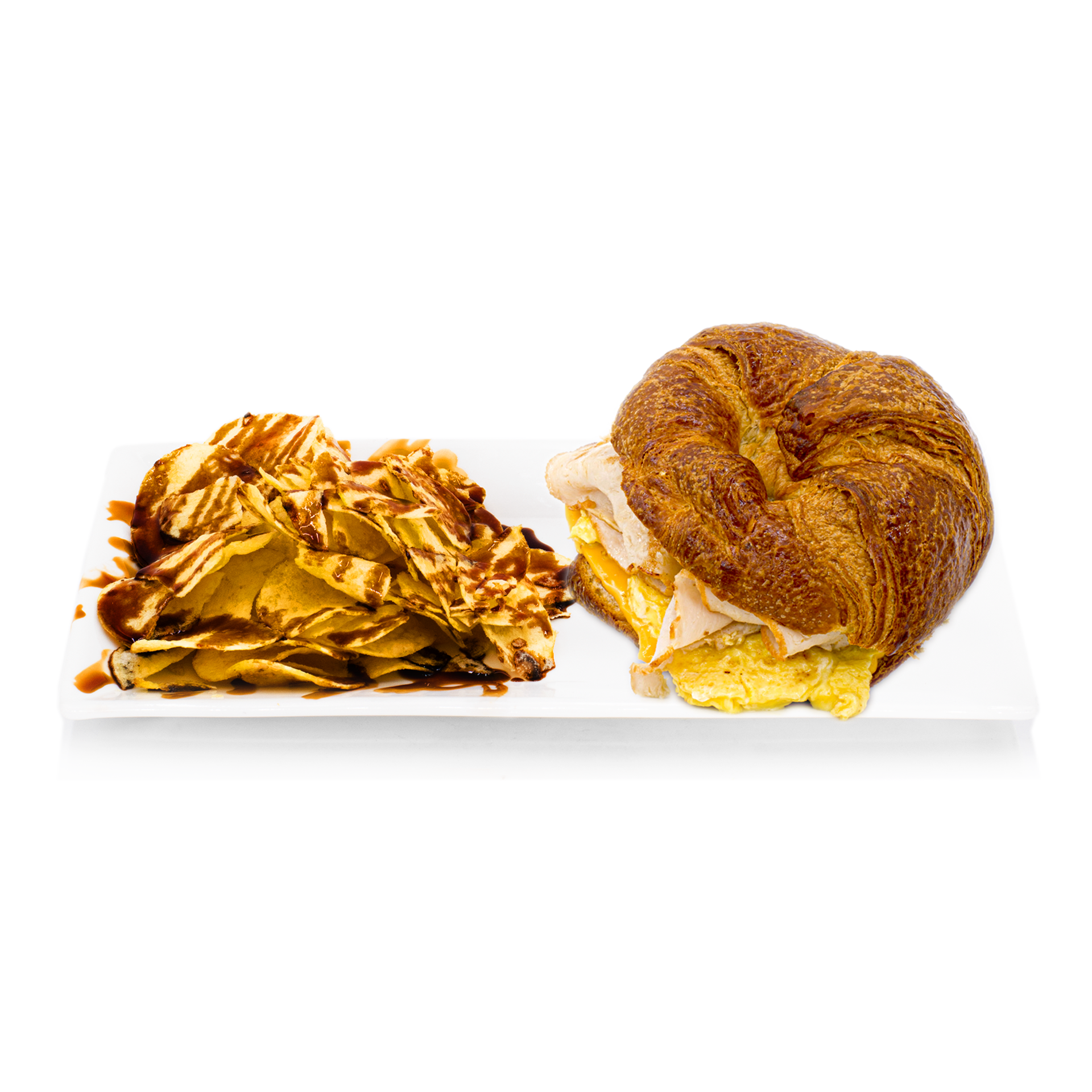 Croissant sandwich with egg, cheese, turkey and chips drizzled with chocolate sauce on white plate
