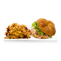 Ham and arugula croissant sandwich with potato chips drizzled with sauce on a white plate