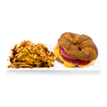 Croissant sandwich with cheddar cheese, salami, and egg served with BBQ-drizzled potato chips