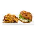 Croissant chicken salad sandwich with arugula served with potato chips drizzled with sauce on a white plate