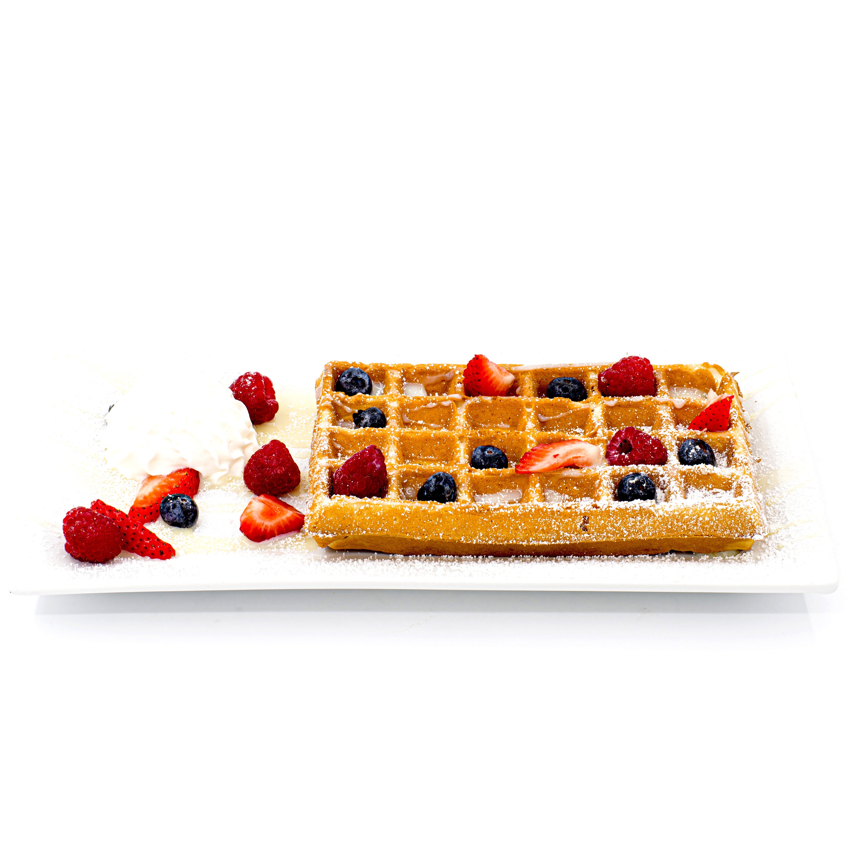 Golden waffle topped with fresh strawberries, blueberries, raspberries, powdered sugar, and whipped cream on a white plate