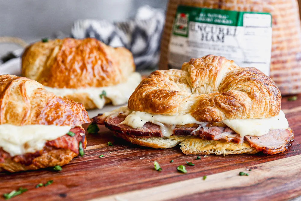 Croissant sandwiches with sliced ham and melted cheese on wooden board