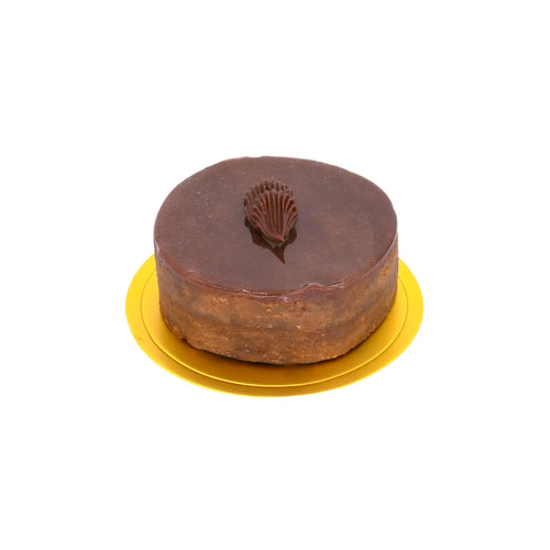Chocolate mousse cake with glossy ganache and decorative chocolate swirl on a yellow base