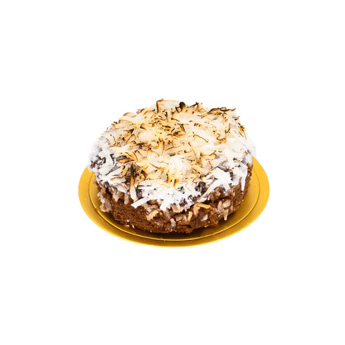 Handcrafted cake topped with toasted coconut flakes on a round golden tray