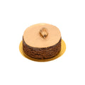 Round chocolate cake with gold dusting and chocolate leaf on top, on gold tray