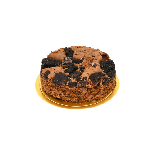 Chocolate cake topped with crushed cookies on a gold plate, isolated on white background