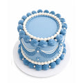 Blue Harmony Cake with elegant light blue and white piped frosting swirls and pearl-like decorations on a white cake board, showcasing a classic custom decorated design.