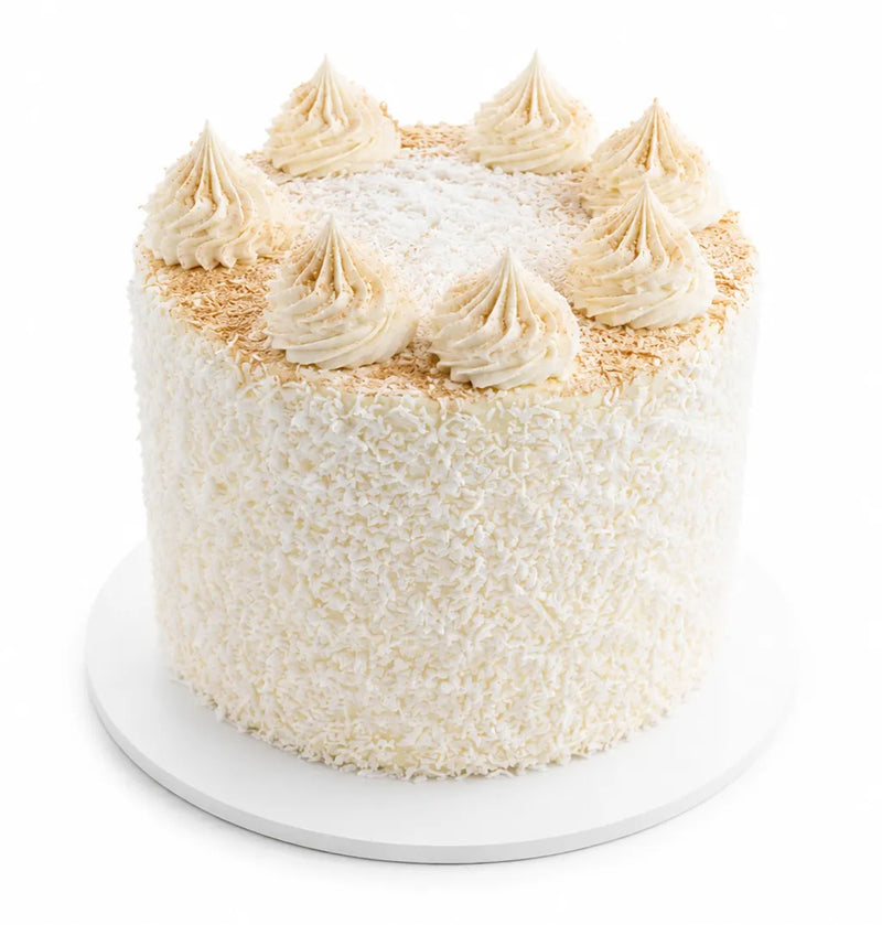 Coconut Cake featuring fluffy white frosting covered in shredded coconut with creamy swirls on top, showcasing a classic and elegant dessert presentation.