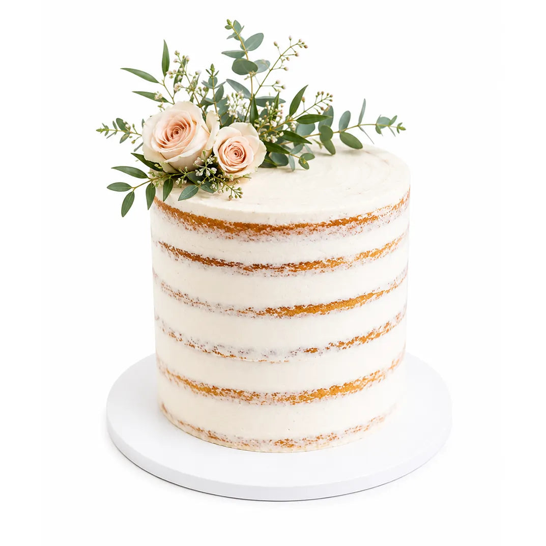 A minimalist Garden Bloom Cake with light buttercream frosting layers and decorated on top with pale pink roses and greenery for an elegant, natural look.