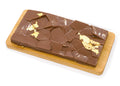 Milk chocolate bar with salted caramel and gold leaf accents on a wooden board