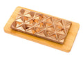 Milk chocolate bar with whole almonds on a geometric surface, displayed on a wooden board