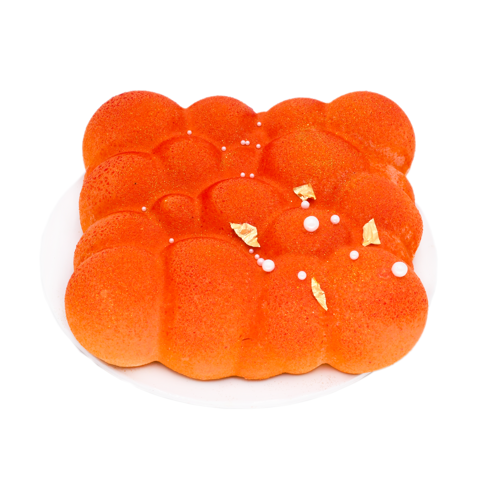 Orange mousse cake with velvet texture, gold leaf and pearl decorations on white plate