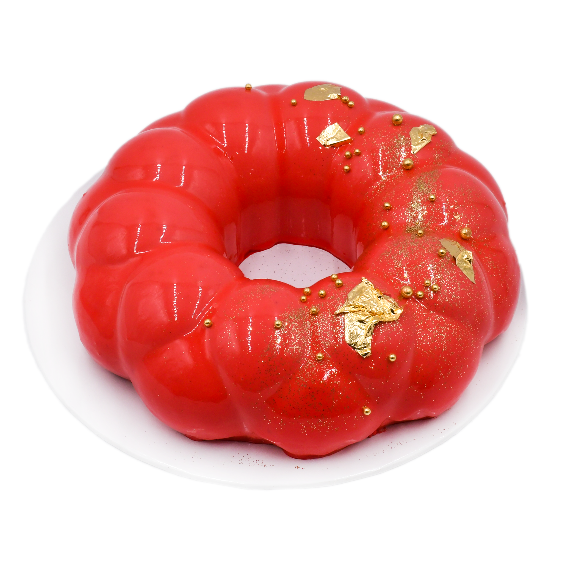 Red velvet mousse cake with glossy glaze and edible gold decorations on white plate