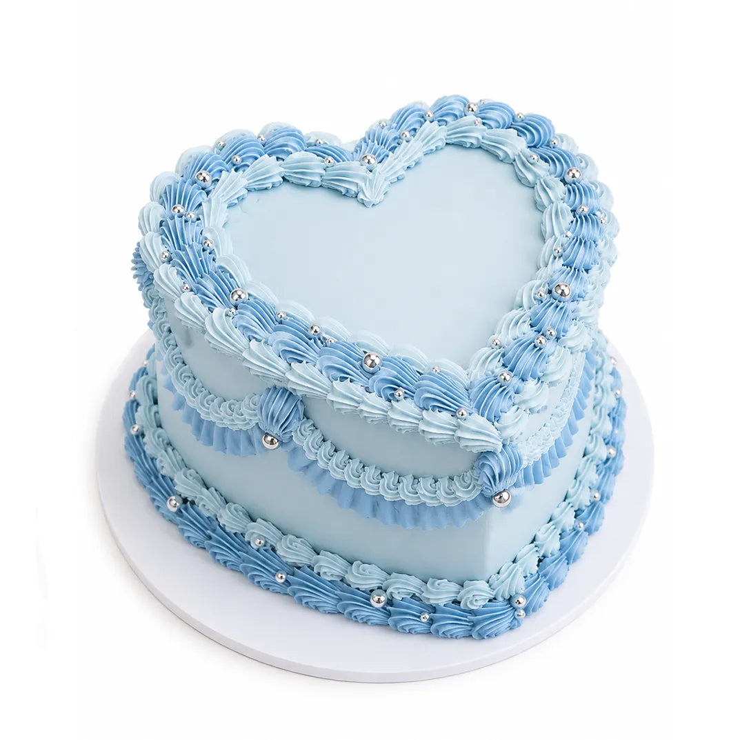 Sky Blue Heart Cake with two tiers decorated in light and medium blue buttercream swirls and silver edible beads, perfect custom cake for special occasions.