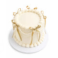 Soft Feelings Cake with smooth white frosting, decorated with piped borders and elegant gold ribbon bows, perfect for custom birthday cakes or luxury desserts.