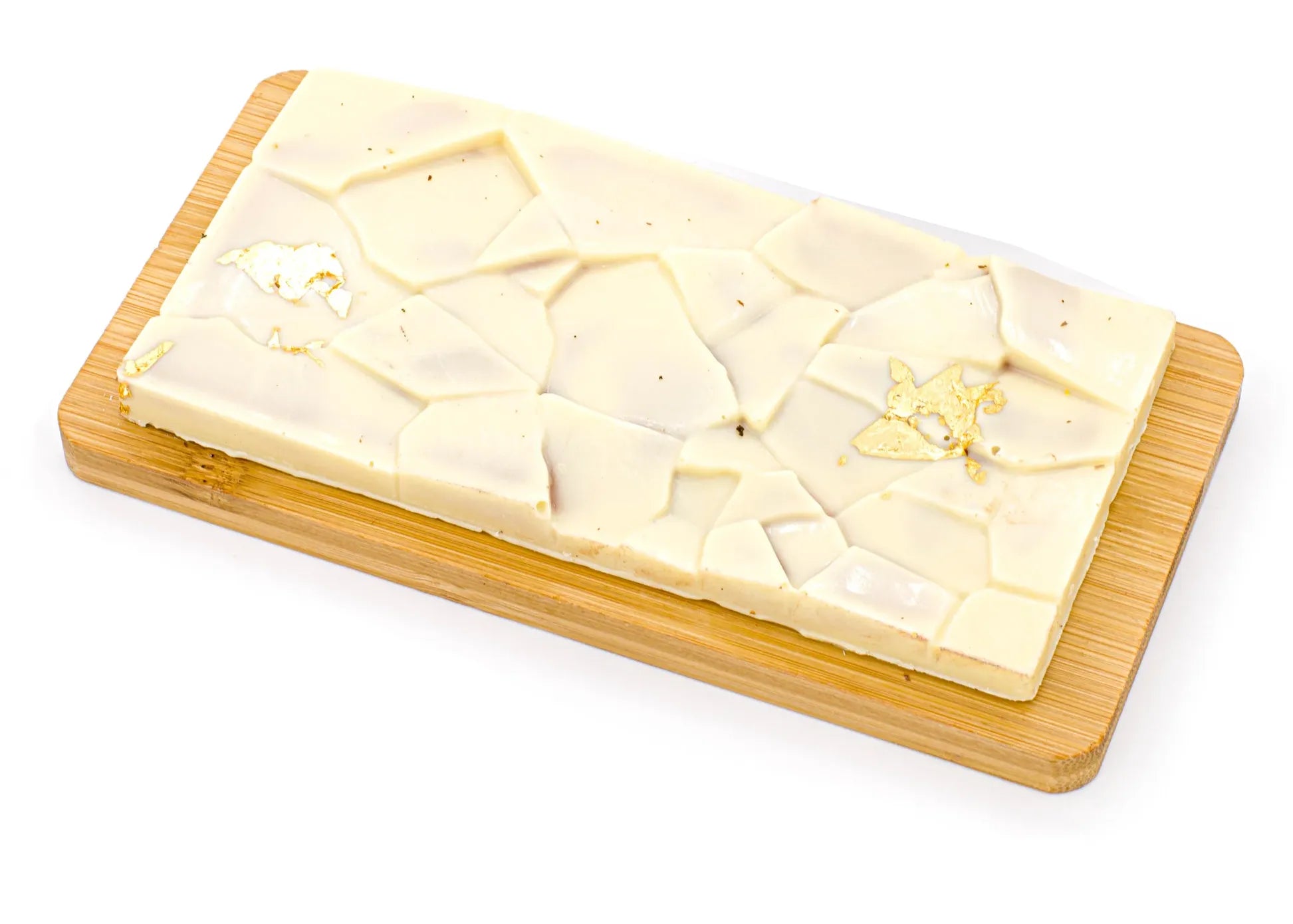 White chocolate bar with caramel and gold accents on a wooden board