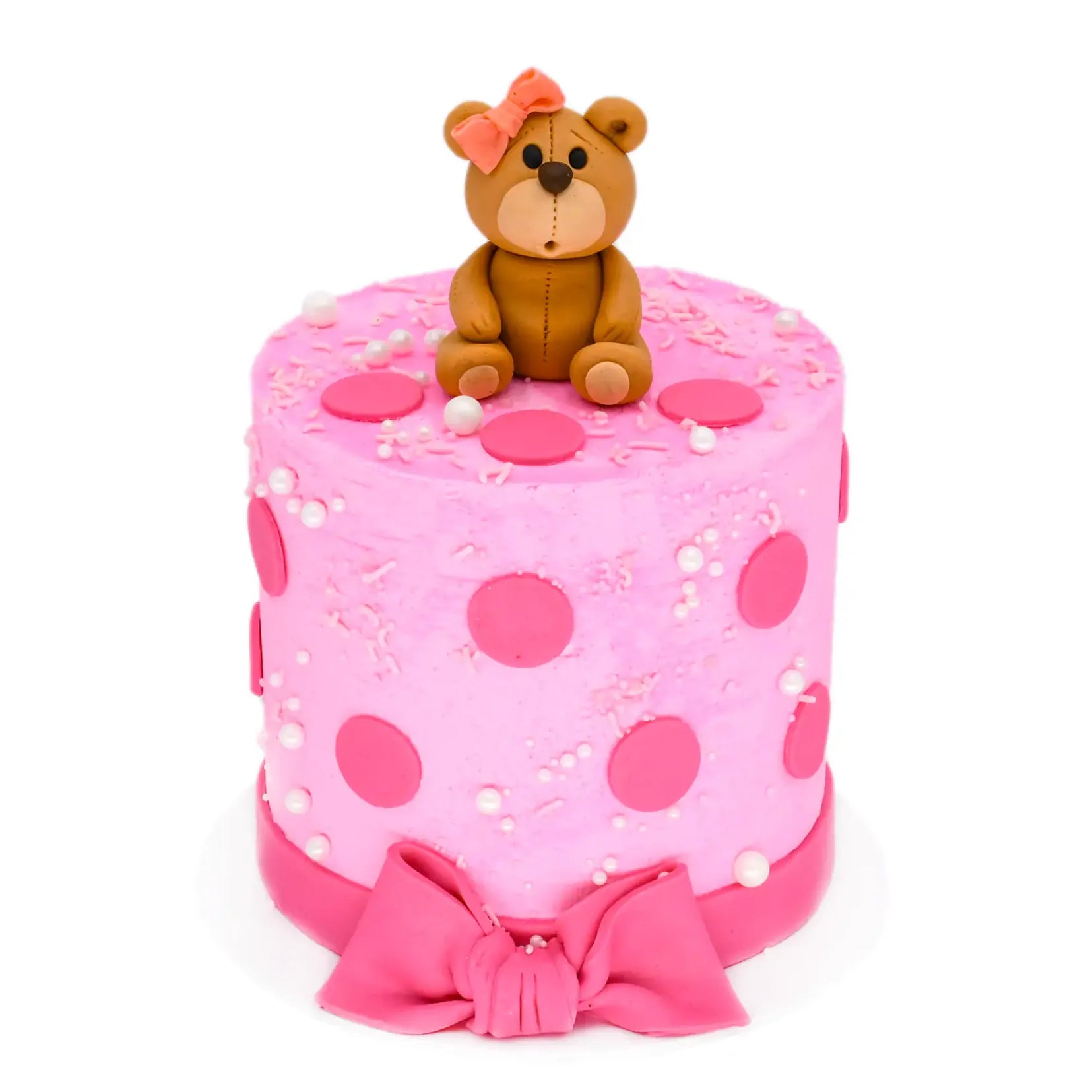 Baby Girl Cake with pink frosting decorated with pink polka dots, white pearls, a pink bow at the base, and a fondant teddy bear with a pink bow on top