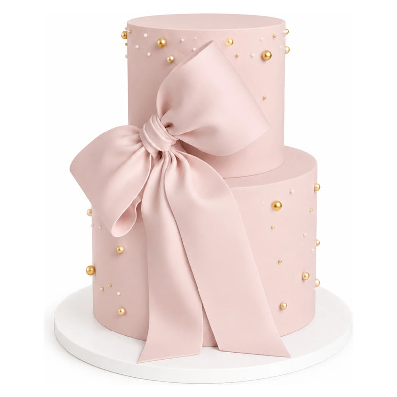 Two Tier Blush Bow Cake featuring a smooth pink fondant finish adorned with delicate gold and white edible pearls and a large elegant blush fondant bow, perfect for luxury celebrations.