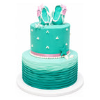 Two-tier teal cake with wave-textured bottom tier, decorated with small white pearl clusters, topped with teal fondant flip-flops adorned with pink stars and white straps, accented with a pink ribbon and starfish on the side.