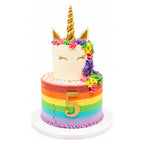 Rainbow Rosette Unicorn Cake with a gold horn, closed-eye face, colorful rosette mane, and a vibrant rainbow-striped base featuring a gold number 5 and sprinkles.