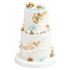 White Gold Seashell Tier Cake featuring three tiers with white fondant, gold accents, and turquoise seashell decorations for a luxurious custom birthday celebration.