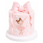 A pastel pink cake with a large bow on top, decorated with small flowers and an illustration of a little ballerina in a pink tutu, titled Little Ballerina Bow Cake.