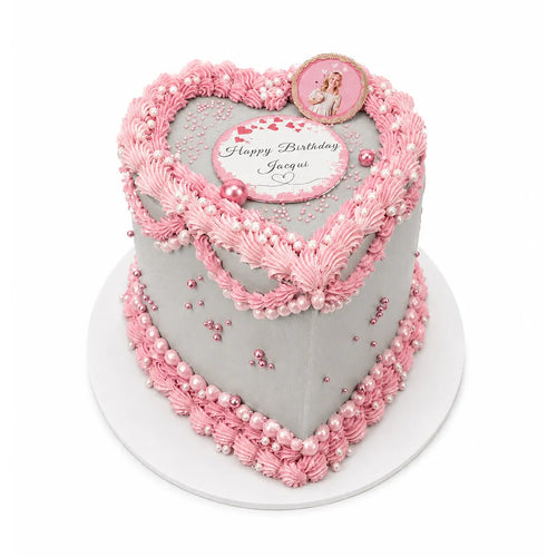 Birthday Princess Heart Cake with elegant pink frosting borders and pearl-like decorations on a smooth gray surface, featuring a personalized birthday message and princess topper.
