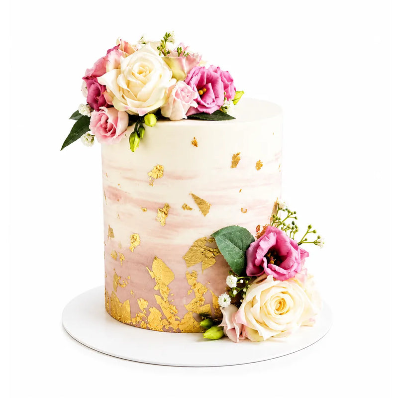 Elegant Golden Garden Cake featuring white and pink floral decorations with gold leaf accents on a smooth white and blush pink gradient icing, perfect for luxury celebrations.