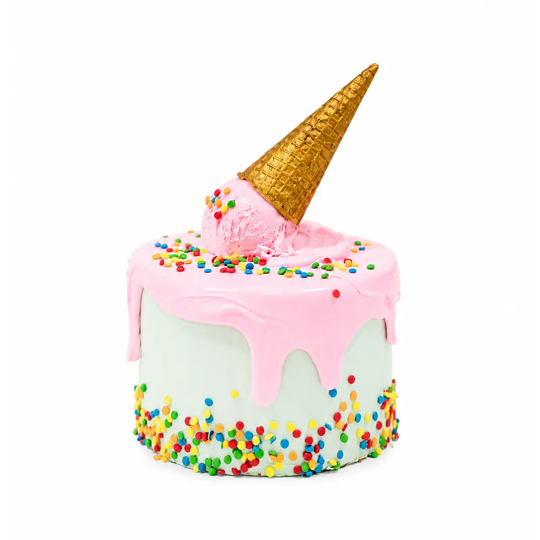 Melted Ice Cream Party Cake featuring white frosting, pink drip icing, colorful sprinkles, and a golden ice cream cone topping designed as a fun custom birthday cake.