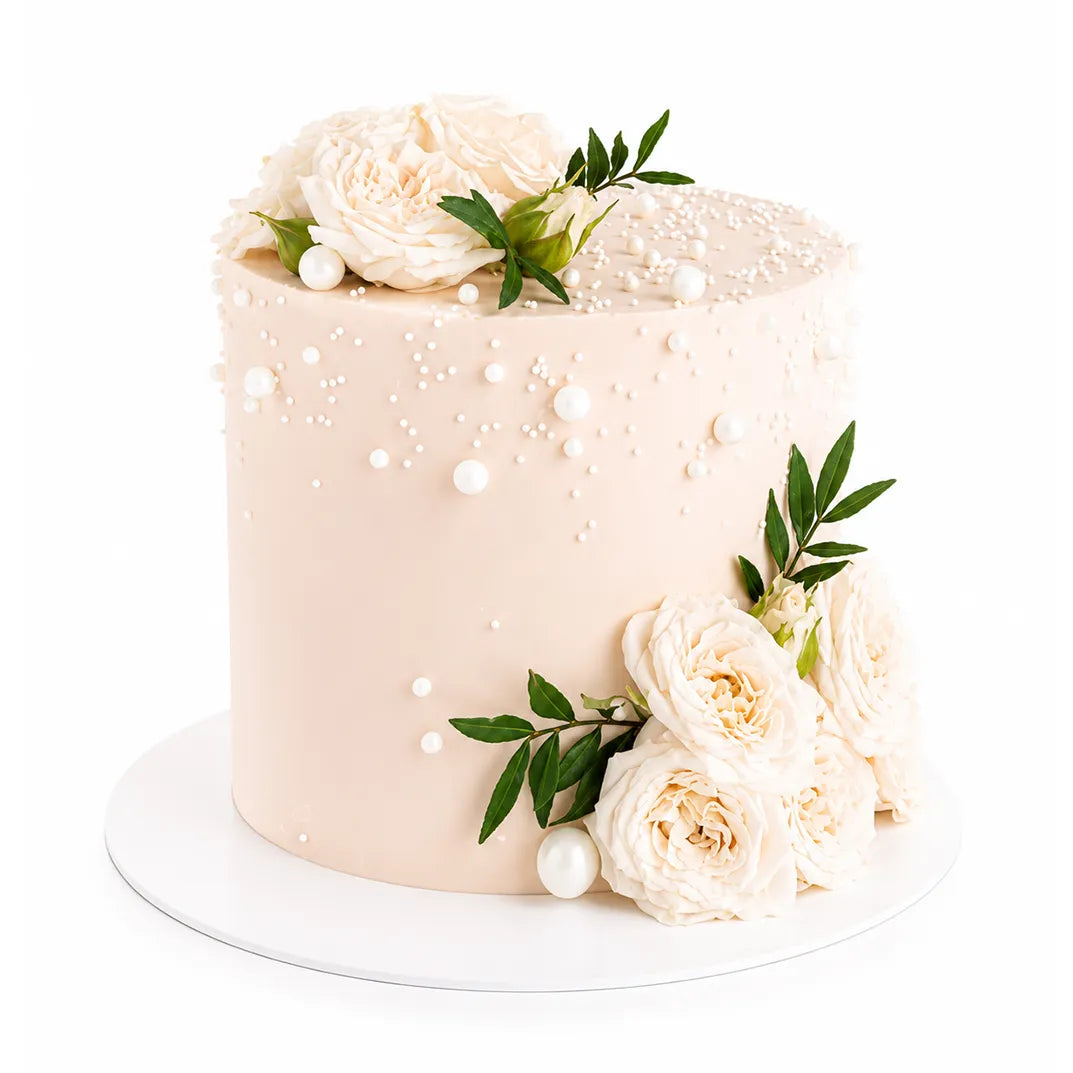 Soft Garden Dream Cake with smooth cream frosting, decorated with delicate white roses, green leaves, and small pearl-like edible decorations for an elegant luxury dessert.
