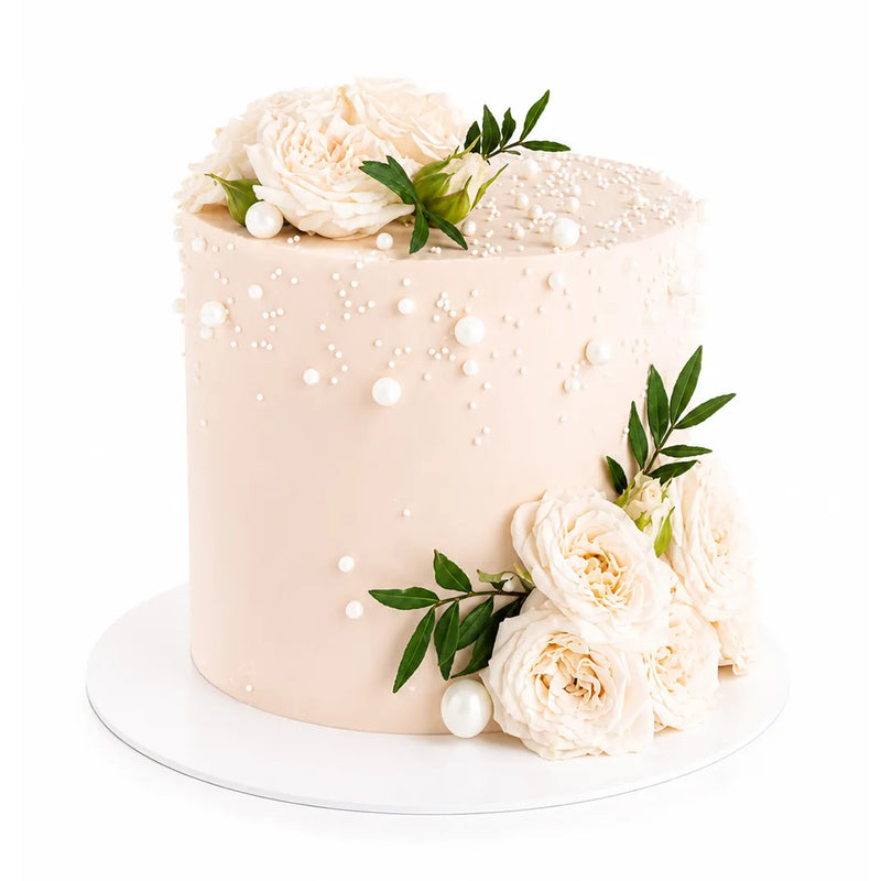 Soft Garden Dream Cake with smooth cream frosting, decorated with delicate white roses, green leaves, and small pearl-like edible decorations for an elegant luxury dessert.