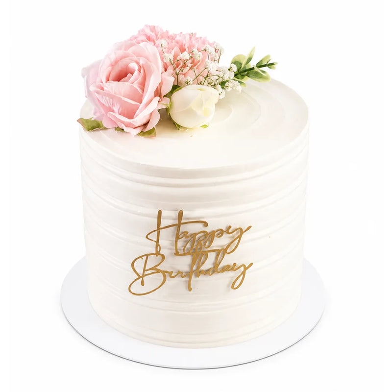 Soft Love Garden Cake featuring smooth white icing decorated with delicate pink and white flowers and a gold "Happy Birthday" topper, perfect for elegant celebrations.