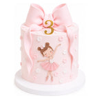 Little Ballerina Bow Cake in soft pink with a large bow on top, decorated with a dancing ballerina and small edible flowers, featuring a gold number 3 for a birthday celebration.