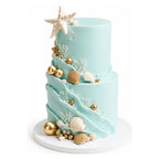 Two-tier teal ocean wave tier cake decorated with white coral, seashells, starfish, and gold spherical accents on a white cake board, custom cakes Los Angeles style.