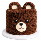 Teddy Bear Cake decorated with textured chocolate frosting to resemble a cute brown bear face with ears, eyes, and a smiling snout on a white cake board