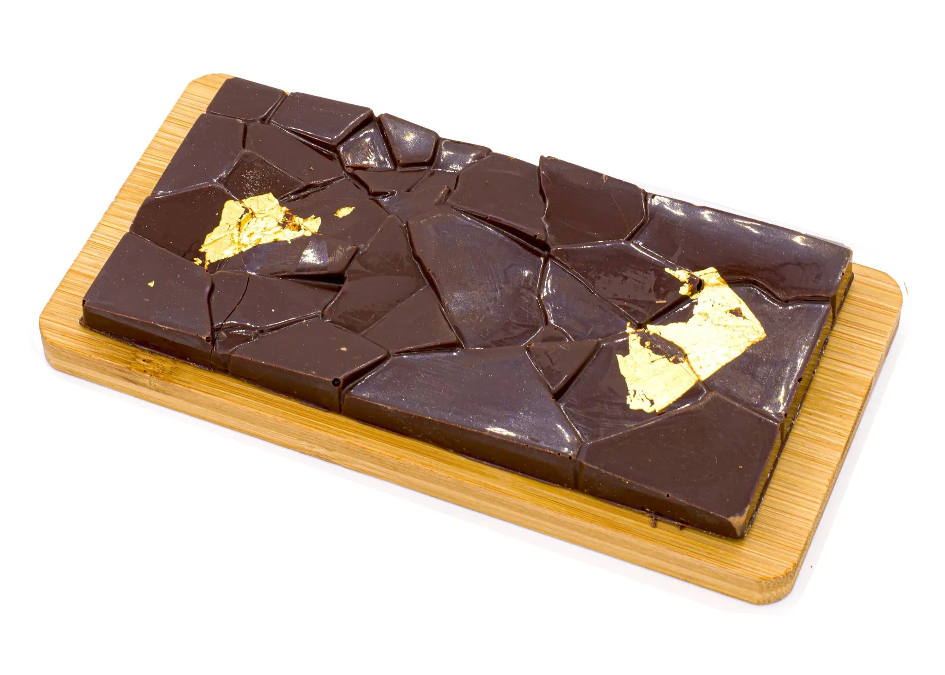 Dark chocolate bar with salted caramel and gold leaf on a wooden board